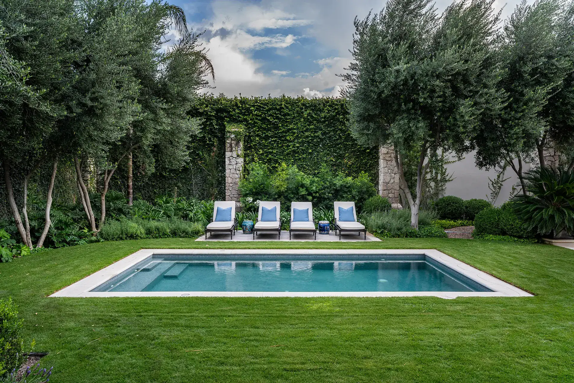 Casa Sienna, swimming pool with four lounge chairs on a lawn surrounded by olive trees and hedges, San Miguel de Allende