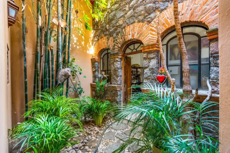 Casa Sirena, stone and brick arched windows of the house among bamboo, ferns and tropical plants, San Miguel de Allende