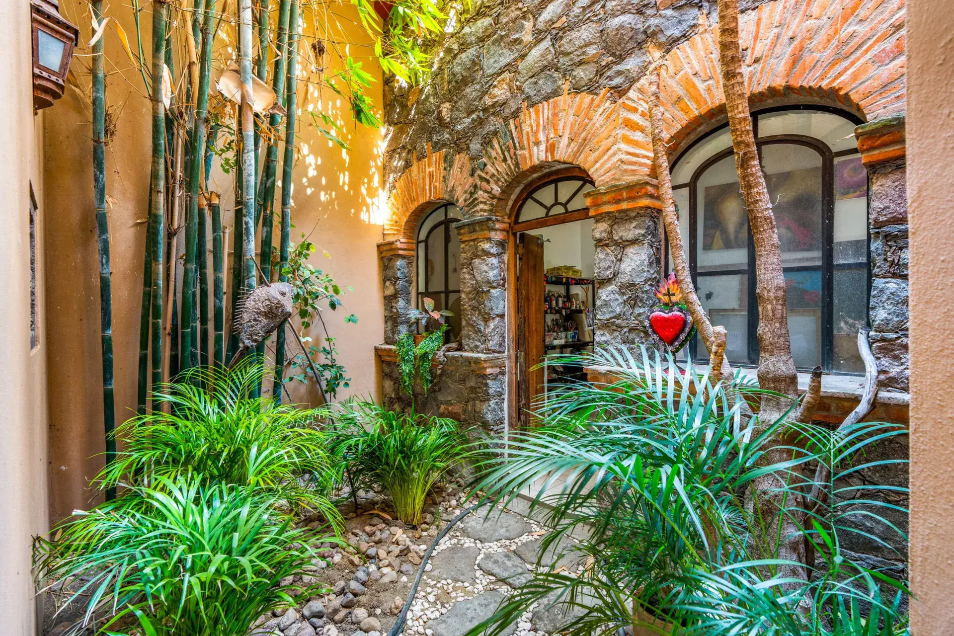 Casa Sirena, stone and brick arched windows of the house among bamboo, ferns and tropical plants, San Miguel de Allende