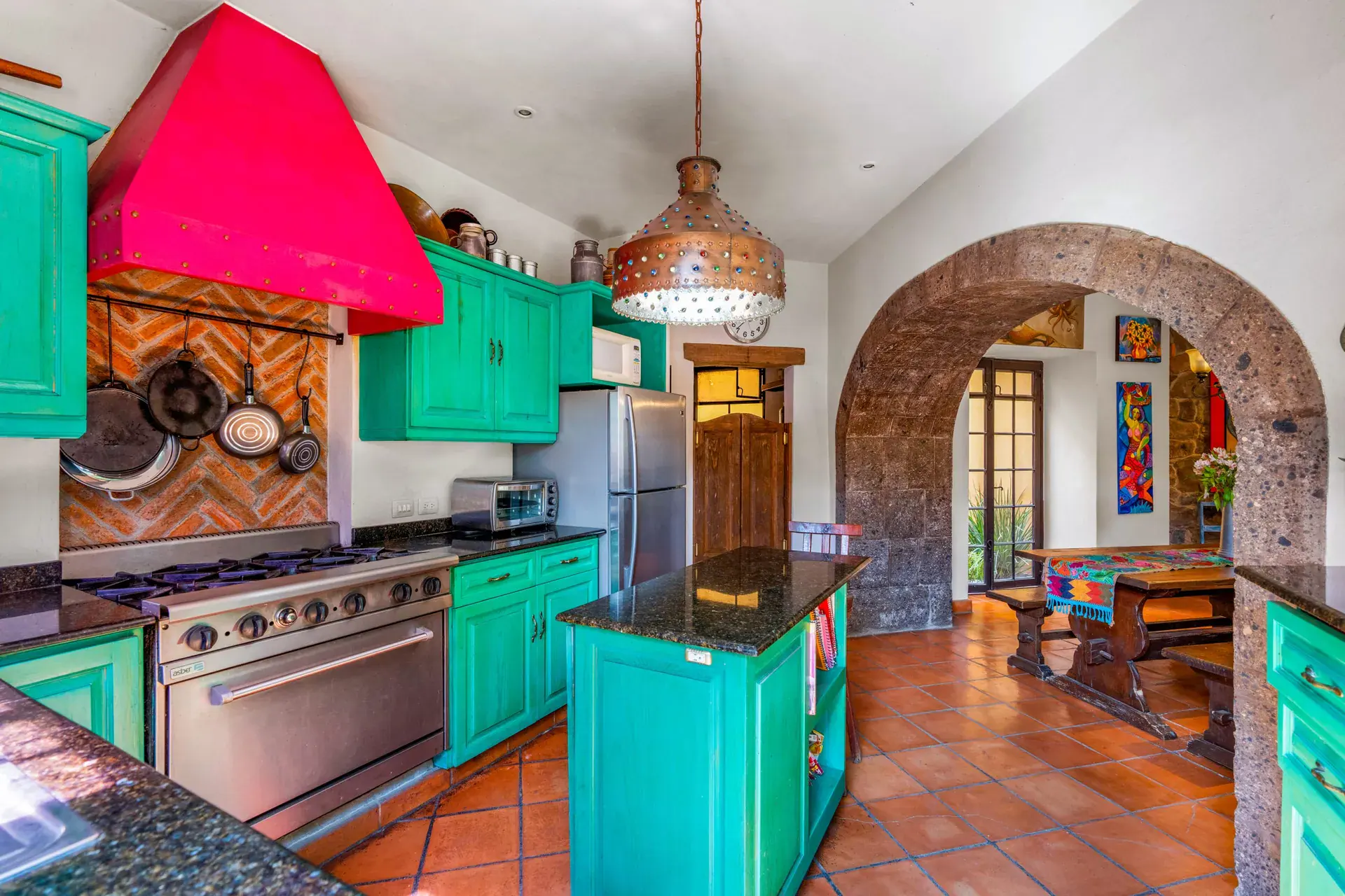 Casa Sirena, kitchen with turquoise cabinets, a magenta range hood, a stainless range and a black granite island, San Miguel de Allende