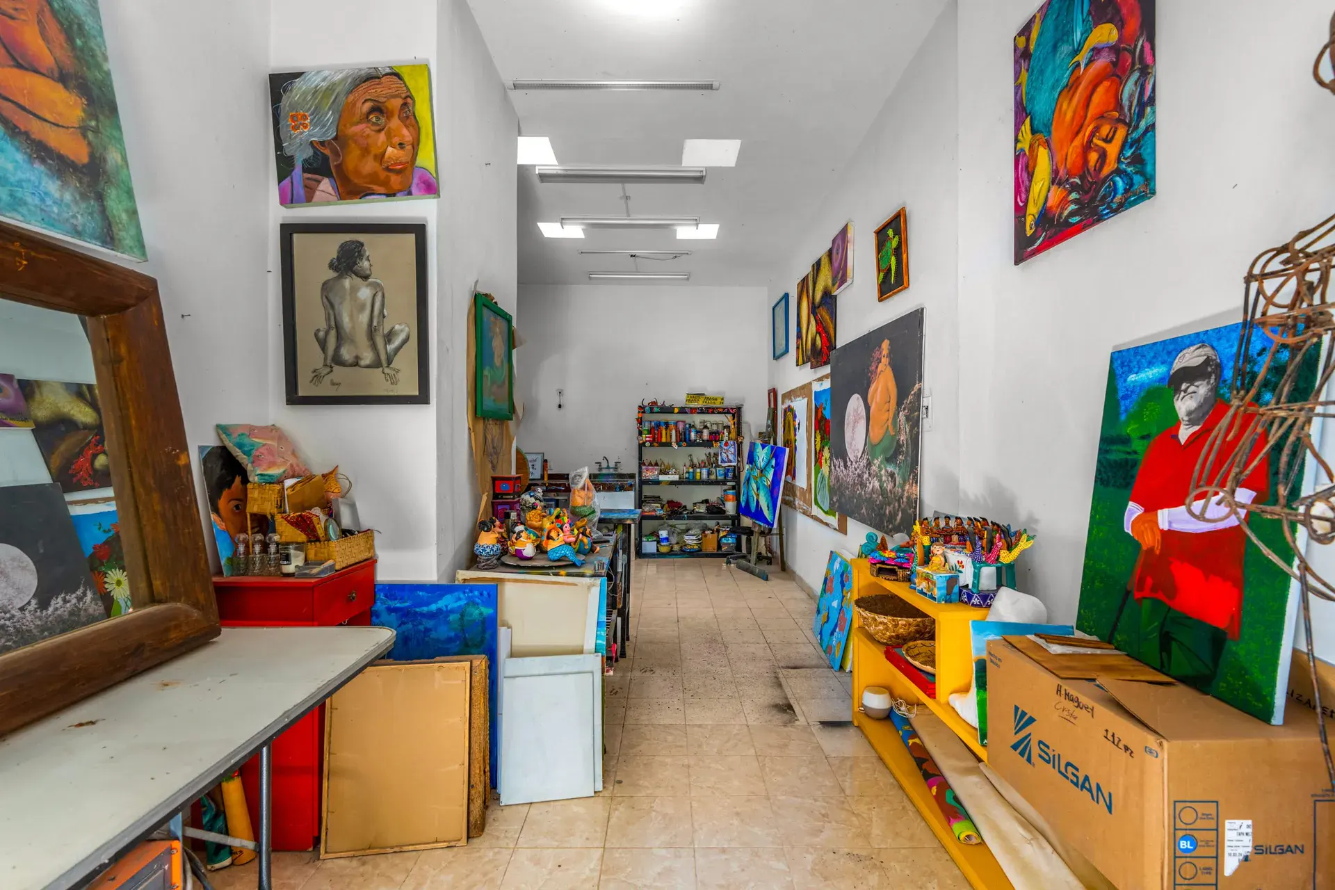 Casa Sirena, studio with a long workroom, paintings on the walls, a mirror and a table with supplies, San Miguel de Allende