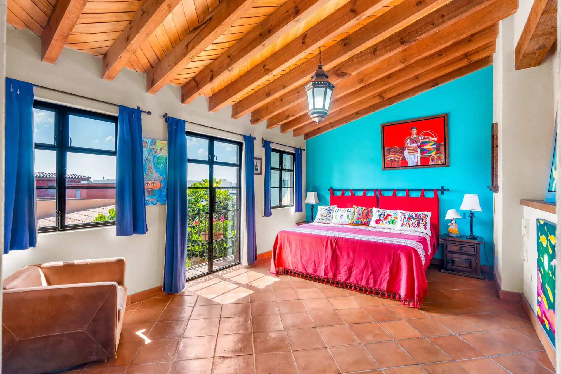 Casa Sirena, bedroom with a turquoise wall, a red bedspread, large windows and a view of the hills, San Miguel de Allende
