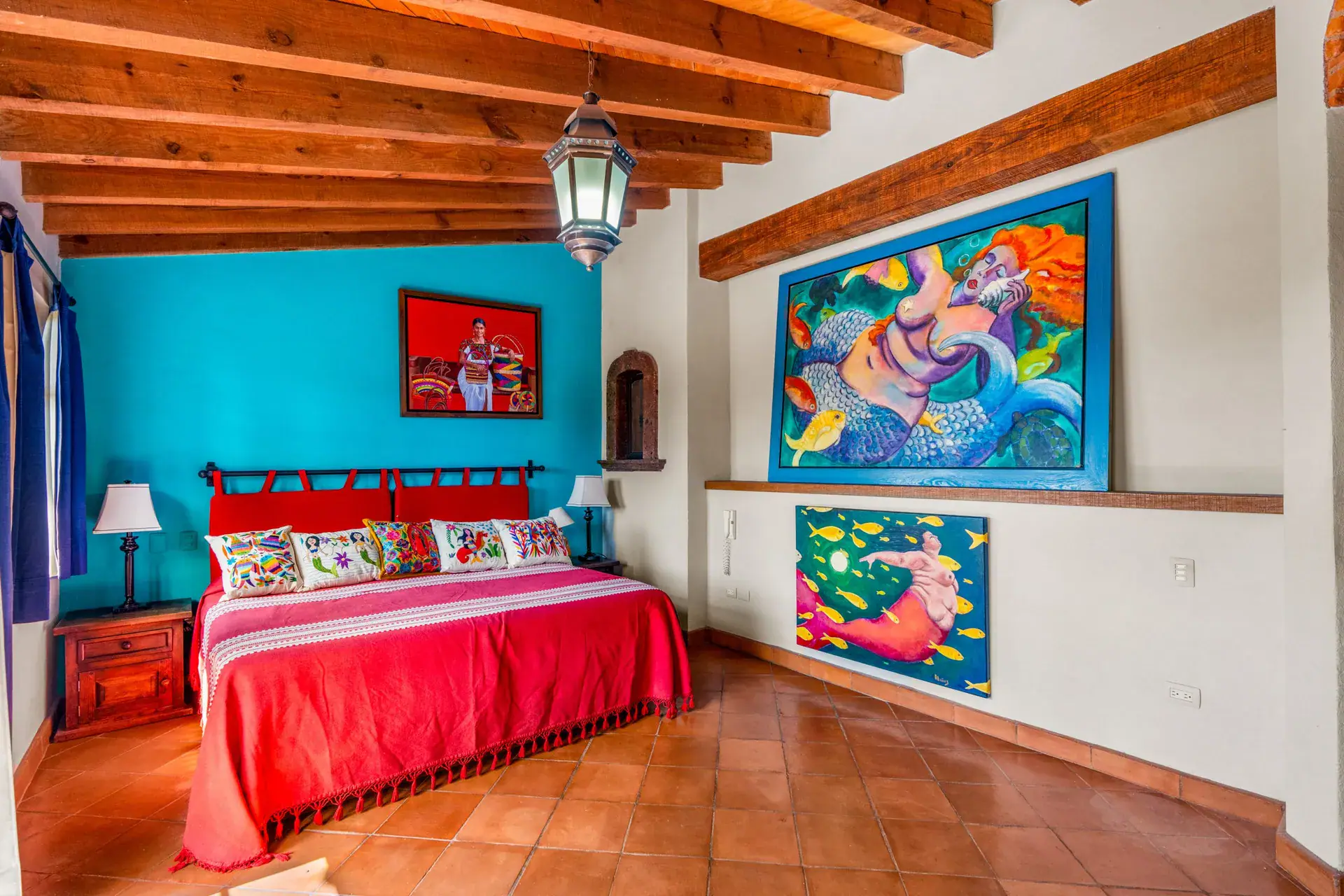 Casa Sirena, bedroom with a turquoise headboard wall, a red bed and a mermaid painting, San Miguel de Allende