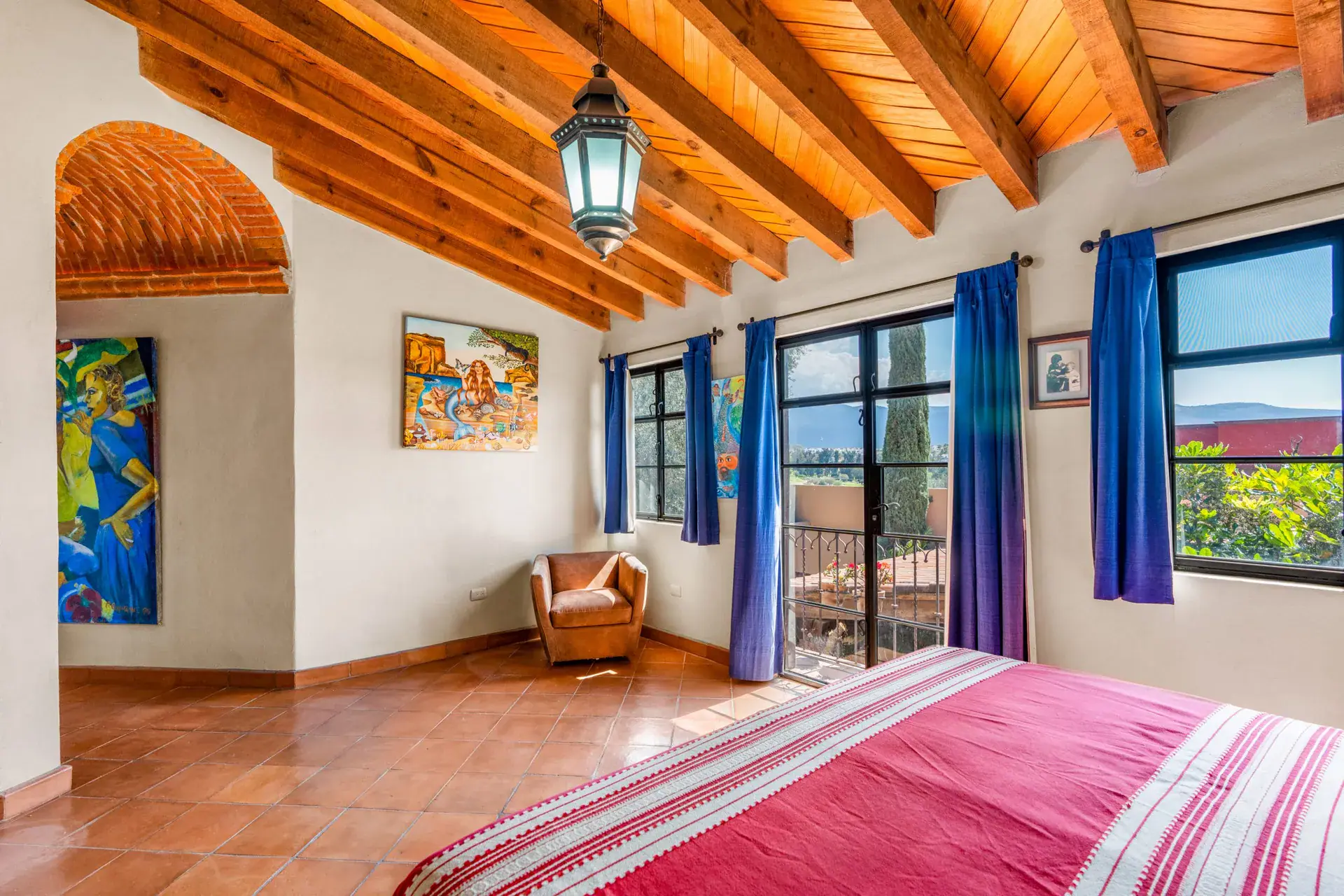 Casa Sirena, bedroom corner with an armchair, a painting and glass doors to a balcony, San Miguel de Allende