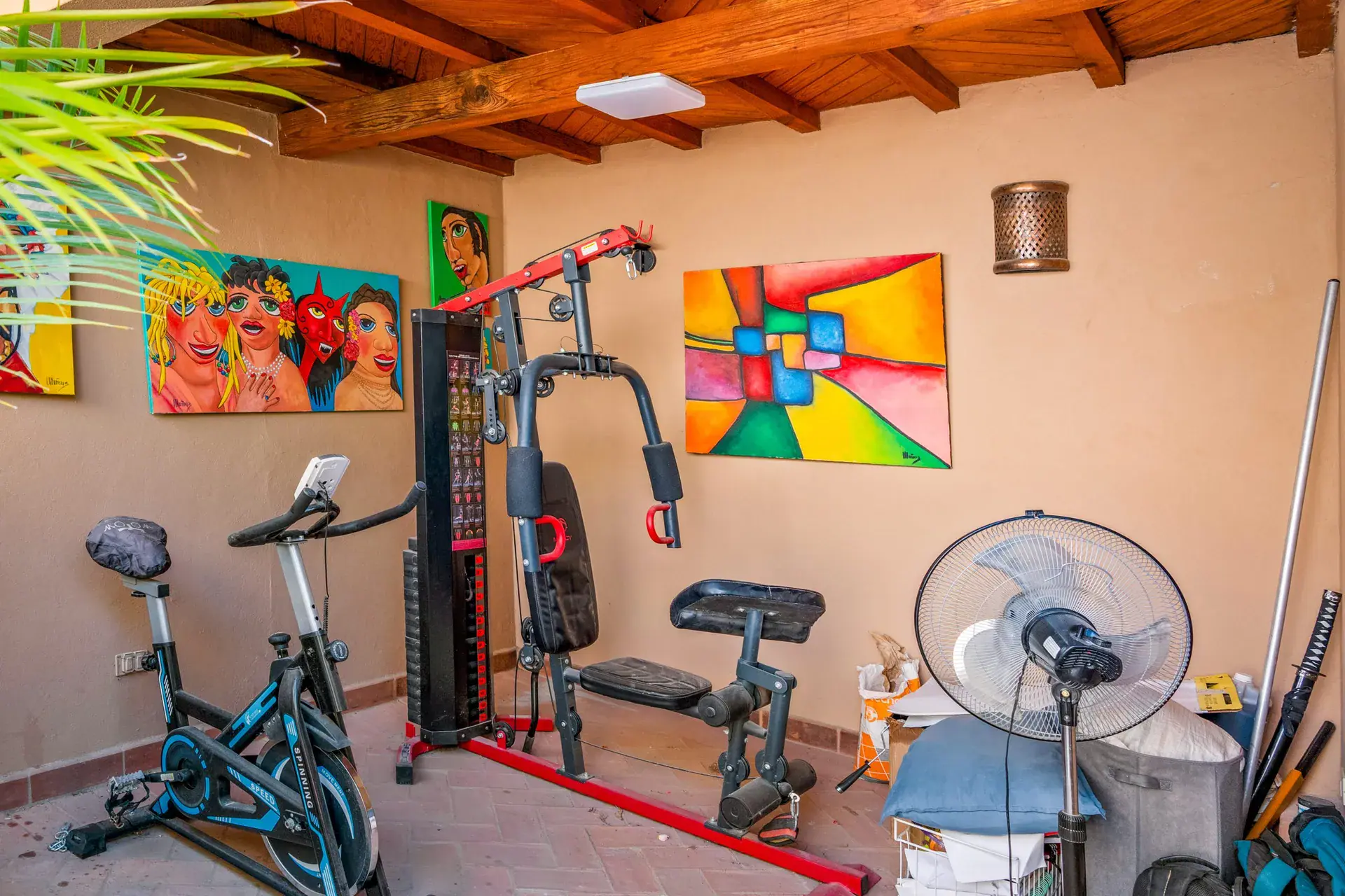 Casa Sirena, exercise room with a stationary bike, a home gym machine, paintings and a timber ceiling, San Miguel de Allende