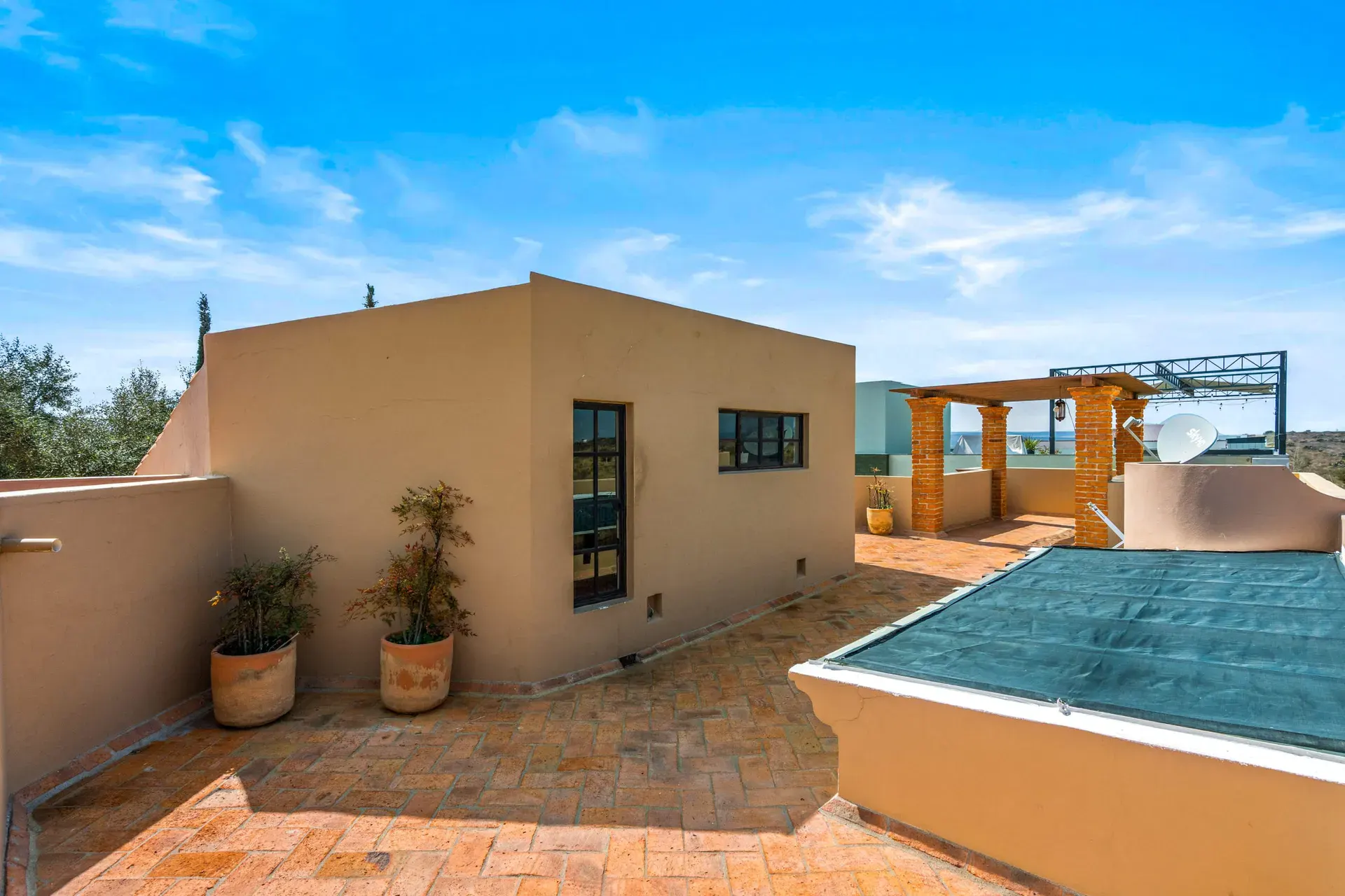 Casa Sirena, rooftop terrace with a brick floor, planters and a green shade cover, San Miguel de Allende