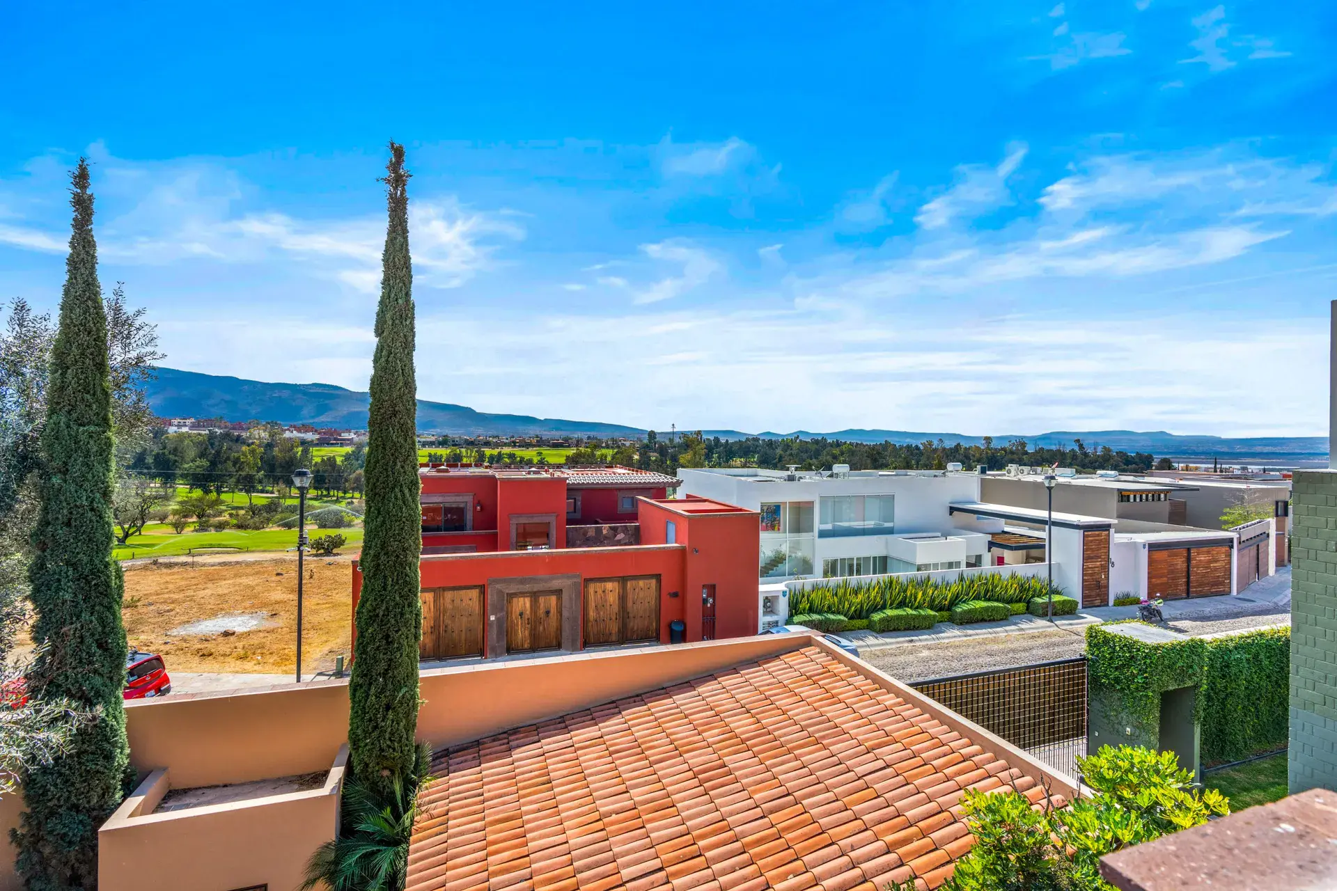 Casa Sirena, view of the golf course, mountains and a red house from the roof, San Miguel de Allende