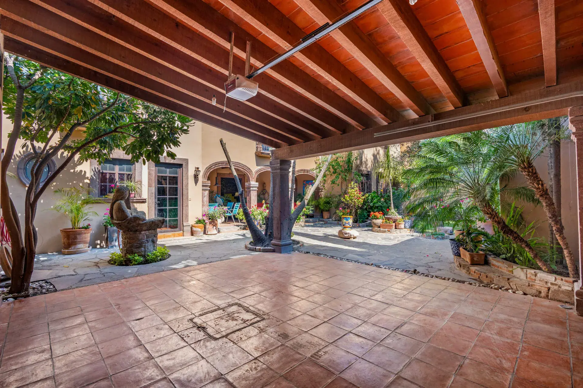 Casa Sirena, covered patio with a tile floor, a timber roof and a view to the courtyard garden and a stone figure, San Miguel de Allende