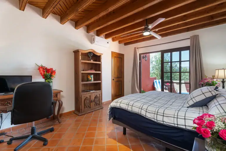 Casa Texican, bedroom with a beamed ceiling and a plaid bedspread, San Miguel de Allende
