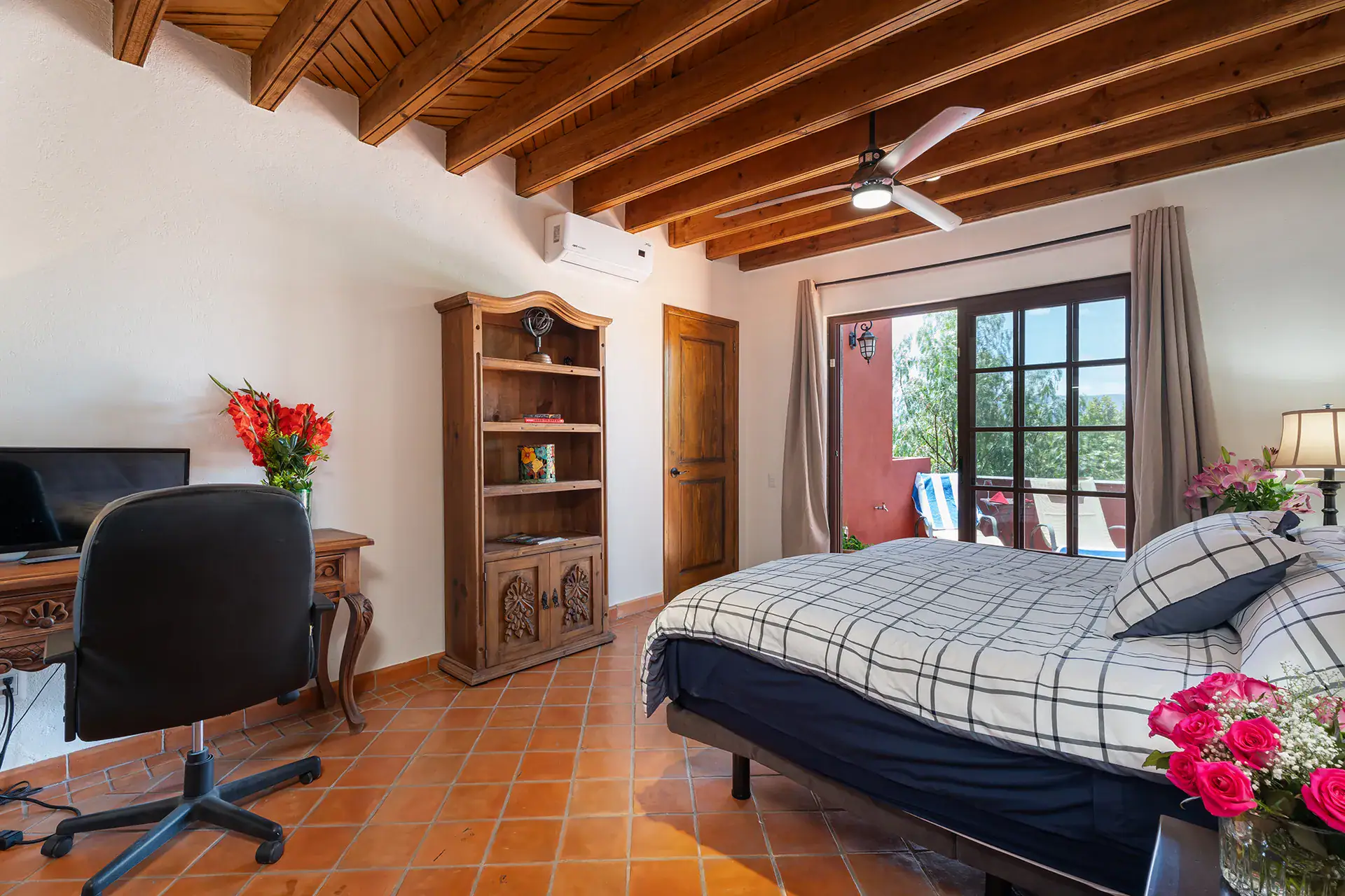 Casa Texican, bedroom with a beamed ceiling and a plaid bedspread, San Miguel de Allende