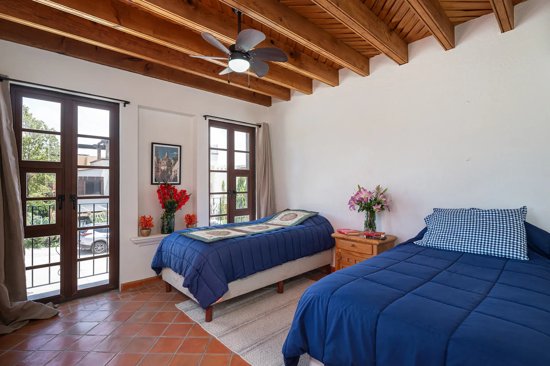 Casa Texican, bedroom with two beds and French doors under a wood beam ceiling, San Miguel de Allende