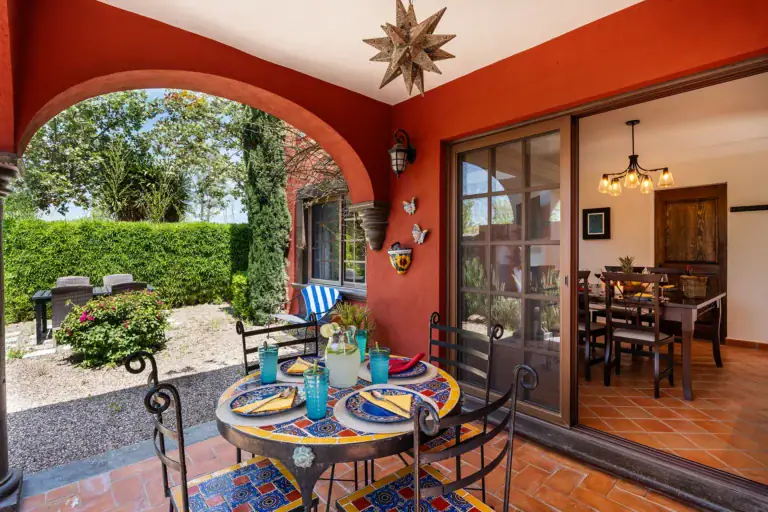 Casa Texican, covered patio with a mosaic table under red arches, San Miguel de Allende