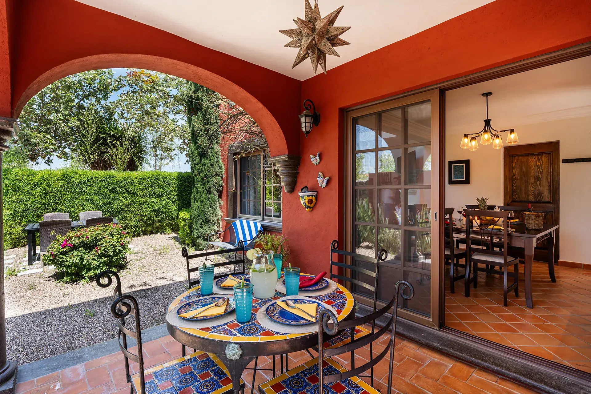 Casa Texican, covered patio with a mosaic table under red arches, San Miguel de Allende