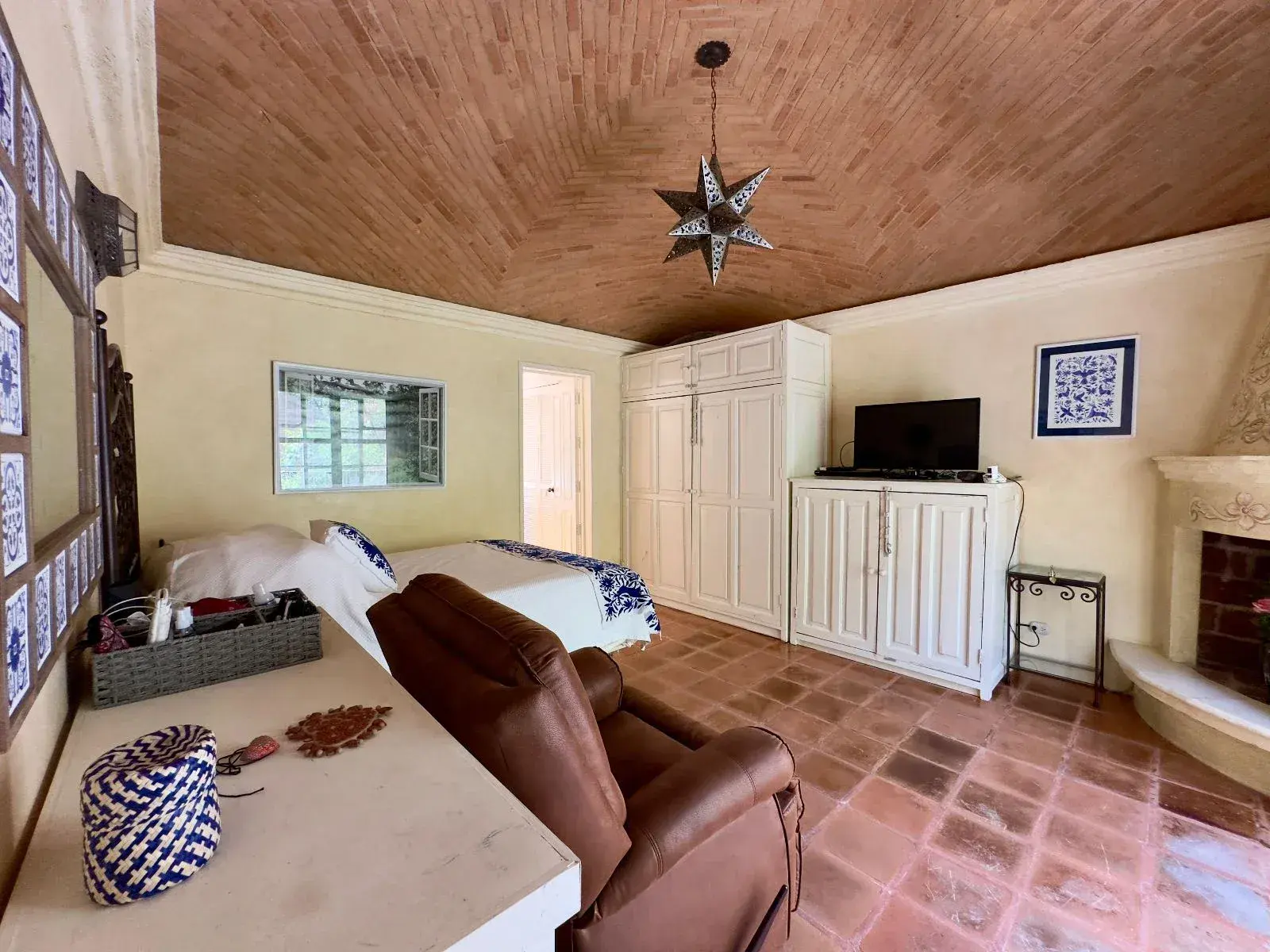 Casa Trebol, bedroom suite with a brick vaulted ceiling, a recliner, a corner fireplace, a television and built-in white cabinets, San Miguel de Allende