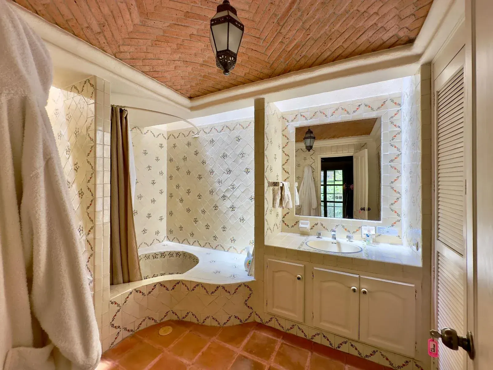 Casa Trebol, bathroom with a sunken tub, a tiled shower, a vanity with cream cabinets and a brick vaulted ceiling, San Miguel de Allende