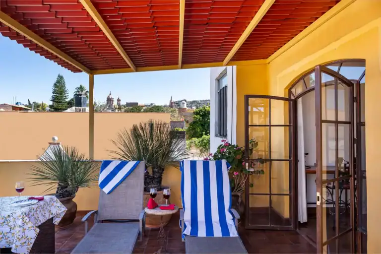 Casa Victoria, rooftop terrace with a red slat roof, lounge chairs and a view of the Parroquia, San Miguel de Allende