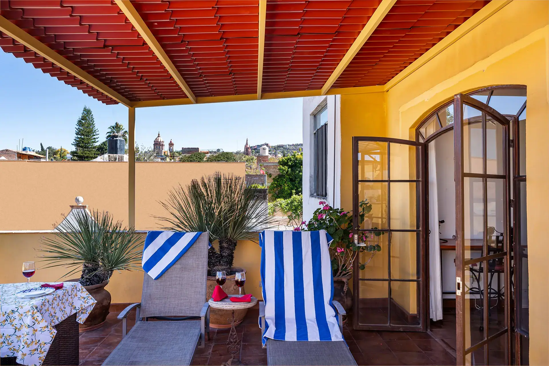 Casa Victoria, rooftop terrace with a red slat roof, lounge chairs and a view of the Parroquia, San Miguel de Allende