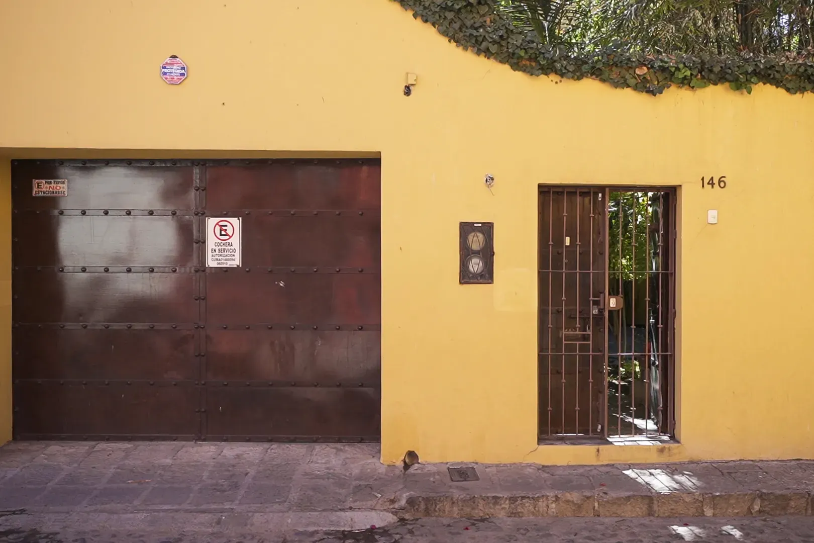 Casa Victoria, yellow facade with a garage door and a street entrance, San Miguel de Allende