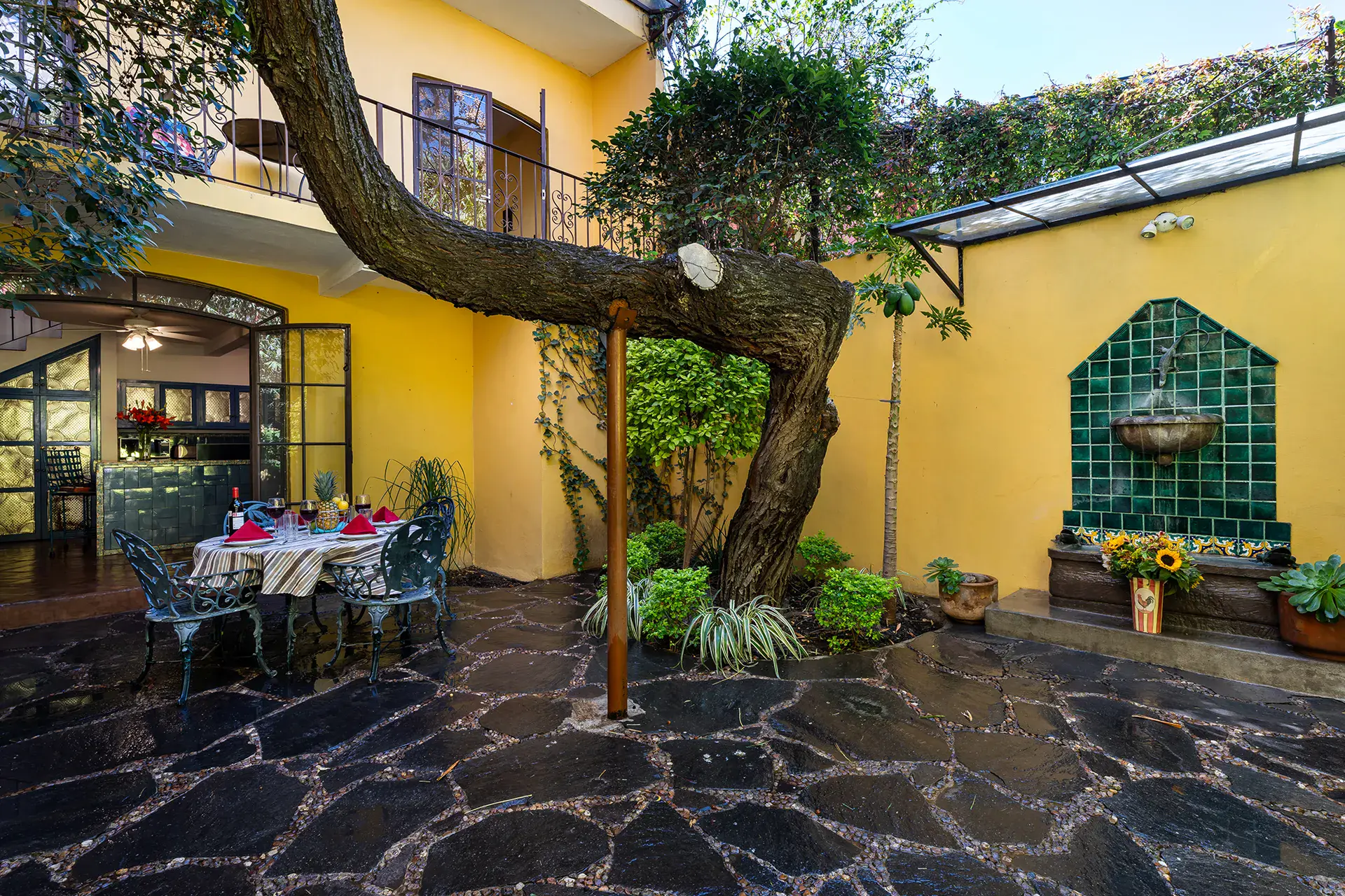 Casa Victoria, flagstone courtyard with a tiled wall fountain and an old tree, San Miguel de Allende