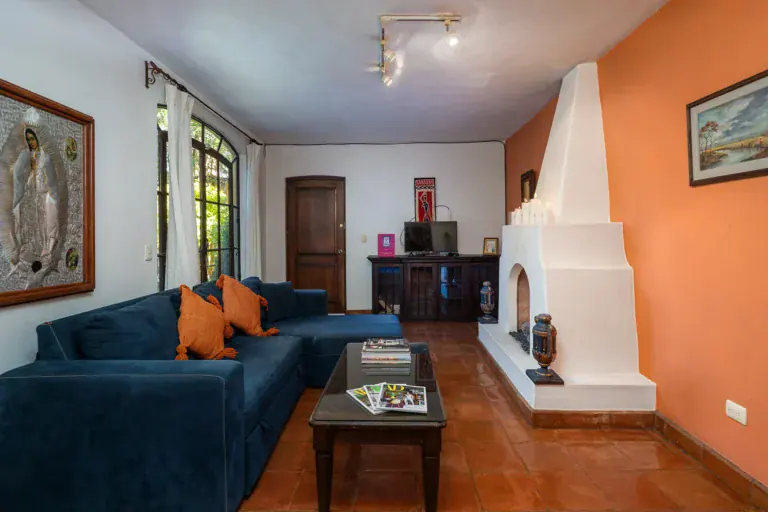Casa Victoria, living room with a blue sectional and a white corner fireplace, San Miguel de Allende