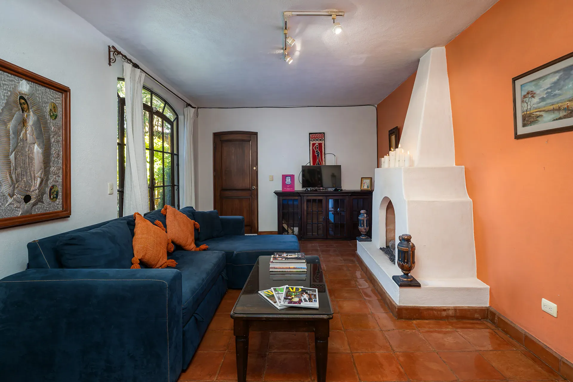 Casa Victoria, living room with a blue sectional and a white corner fireplace, San Miguel de Allende