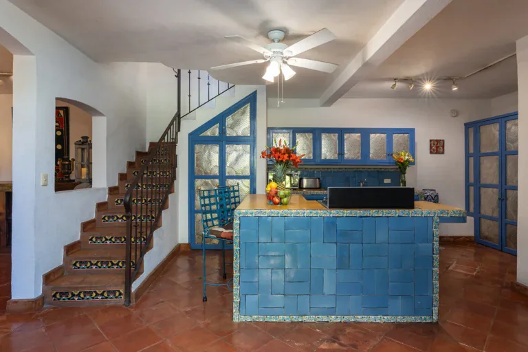 Casa Victoria, kitchen with a blue tile island and a staircase behind it, San Miguel de Allende