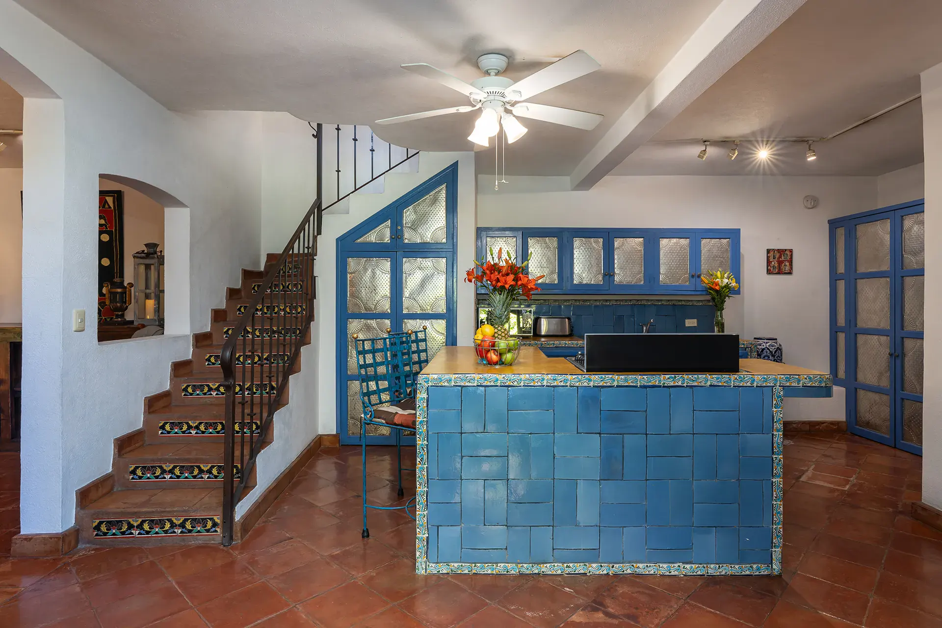 Casa Victoria, kitchen with a blue tile island and a staircase behind it, San Miguel de Allende