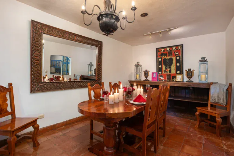 Casa Victoria, dining room with a round wood table, candles and a large mirror, San Miguel de Allende