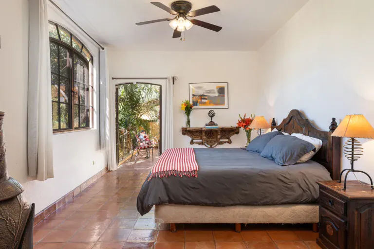 Casa Victoria, bedroom with a carved headboard and a red striped runner, San Miguel de Allende