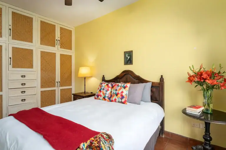 Casa Victoria, yellow bedroom with a carved bed and a built-in wardrobe, San Miguel de Allende