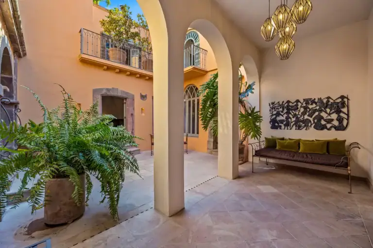 Casa White Magnolias, courtyard arcade with a green daybed, a stone arch, ferns and a hanging brass lantern, San Miguel de Allende