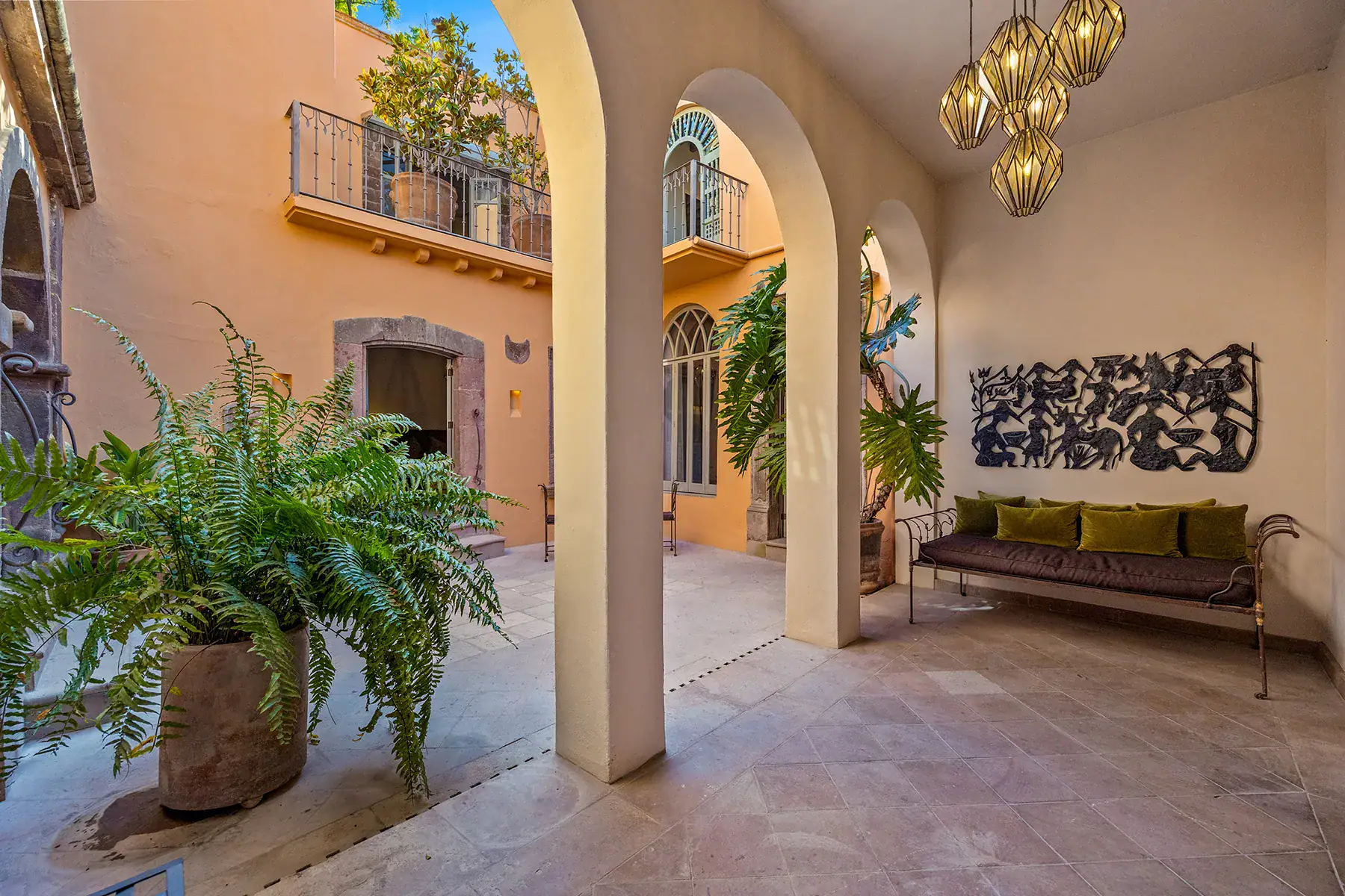 Casa White Magnolias, courtyard arcade with a green daybed, a stone arch, ferns and a hanging brass lantern, San Miguel de Allende