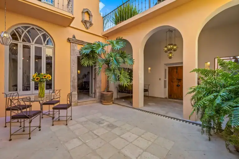 Casa White Magnolias, courtyard bistro table beneath arched windows and a wooden door, San Miguel de Allende