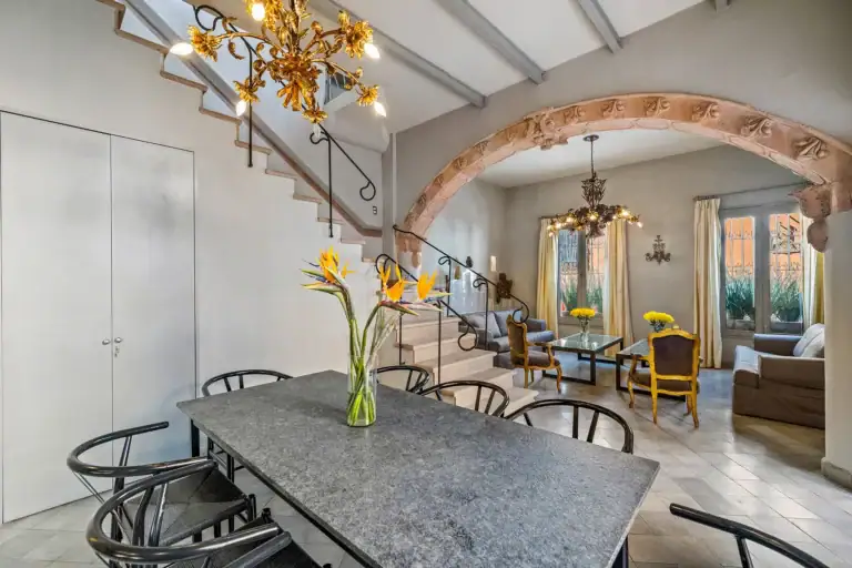 Casa White Magnolias, dining table and stone staircase beneath a gold chandelier, San Miguel de Allende