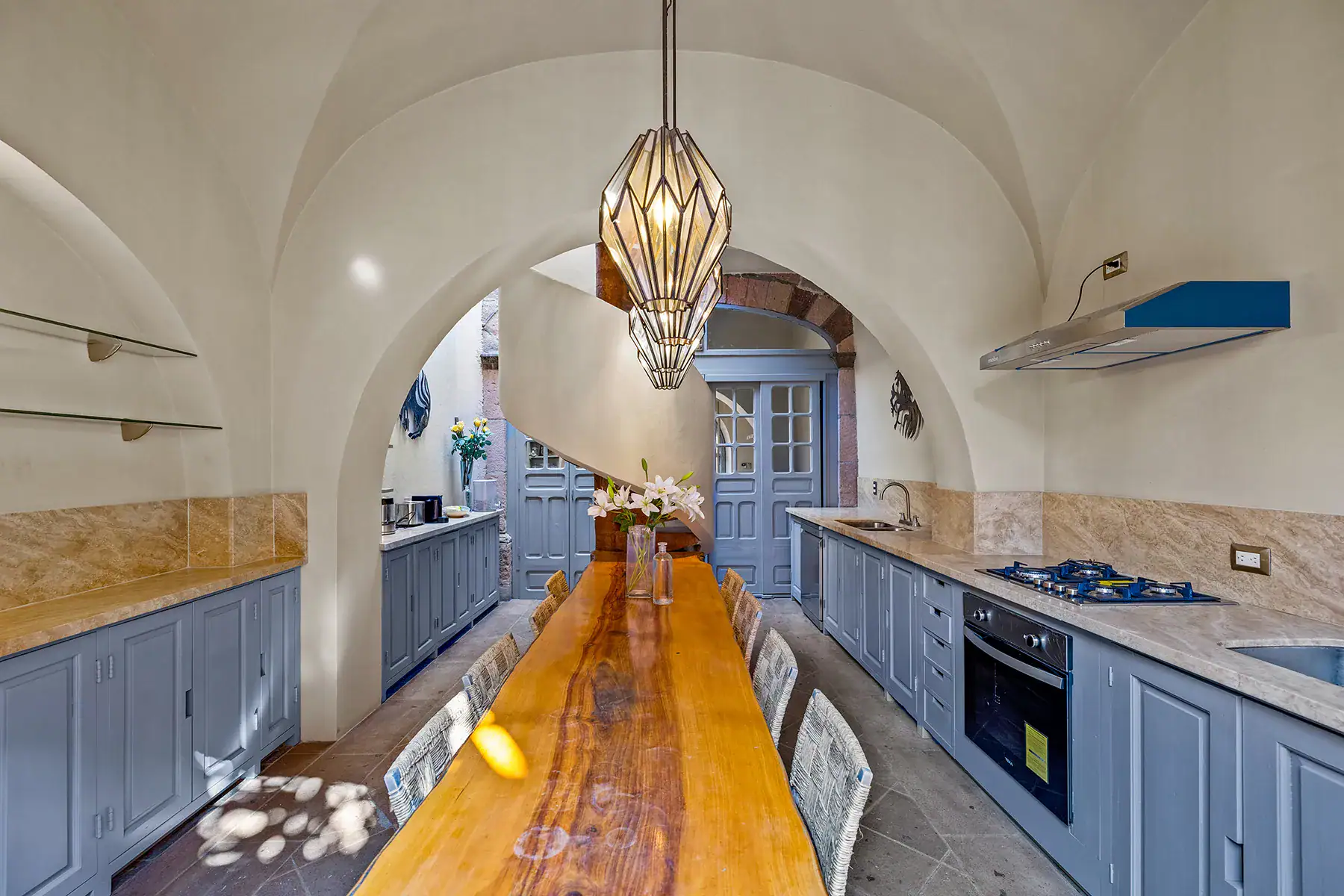 Casa White Magnolias, long kitchen with blue-gray cabinets, a live-edge wood table and a vaulted ceiling, San Miguel de Allende