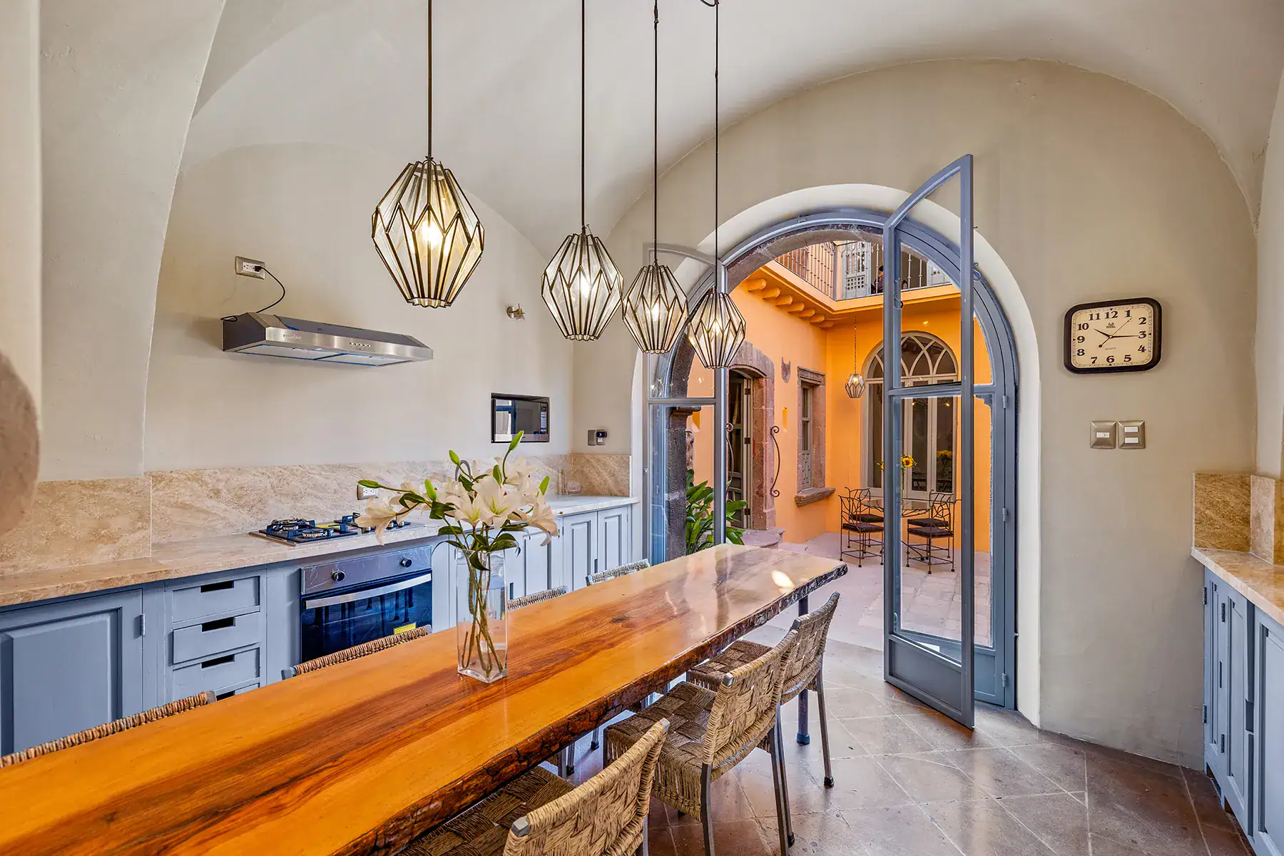 Casa White Magnolias, kitchen with blue cabinets, a gas cooktop and a long wood table beside arched glass doors, San Miguel de Allende