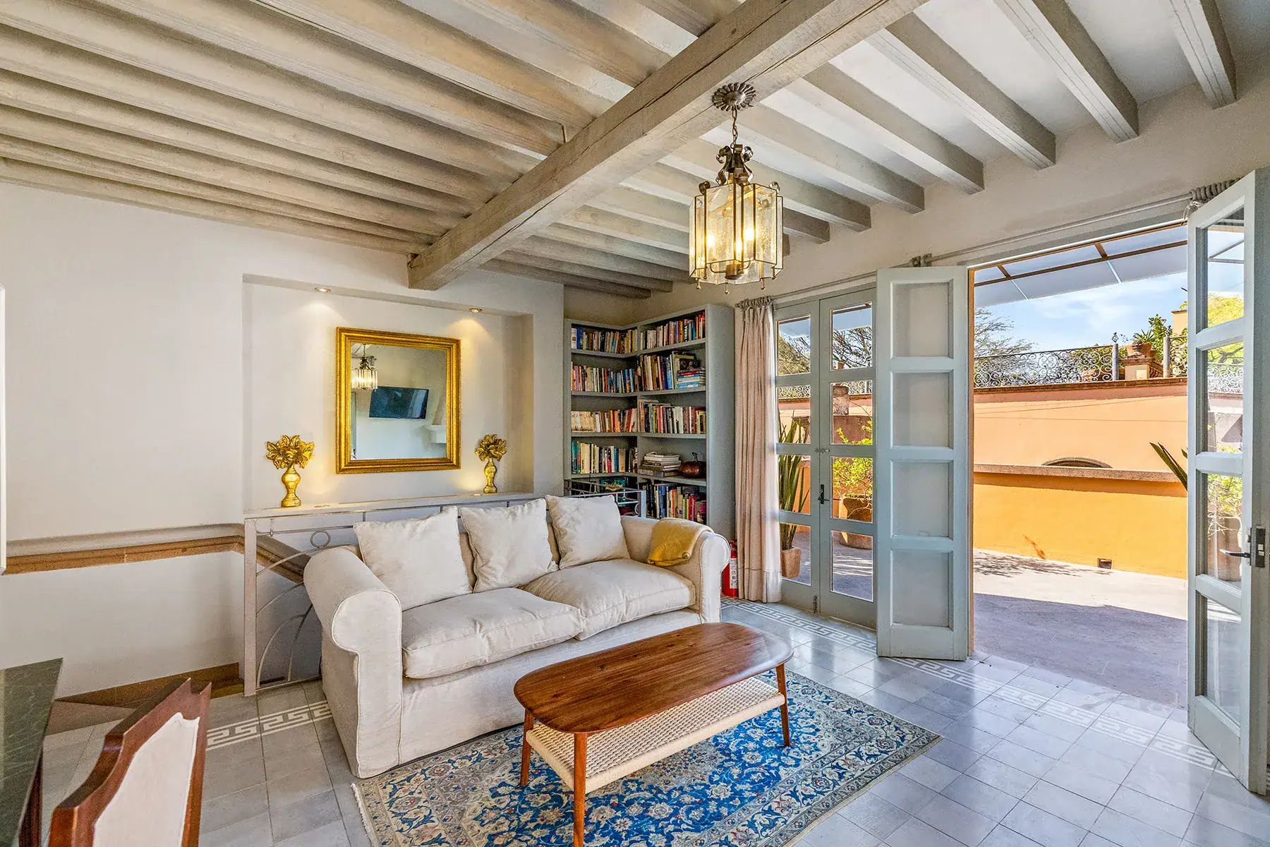 Casa White Magnolias, living room with a white sofa, bookshelves and French doors to a terrace, San Miguel de Allende