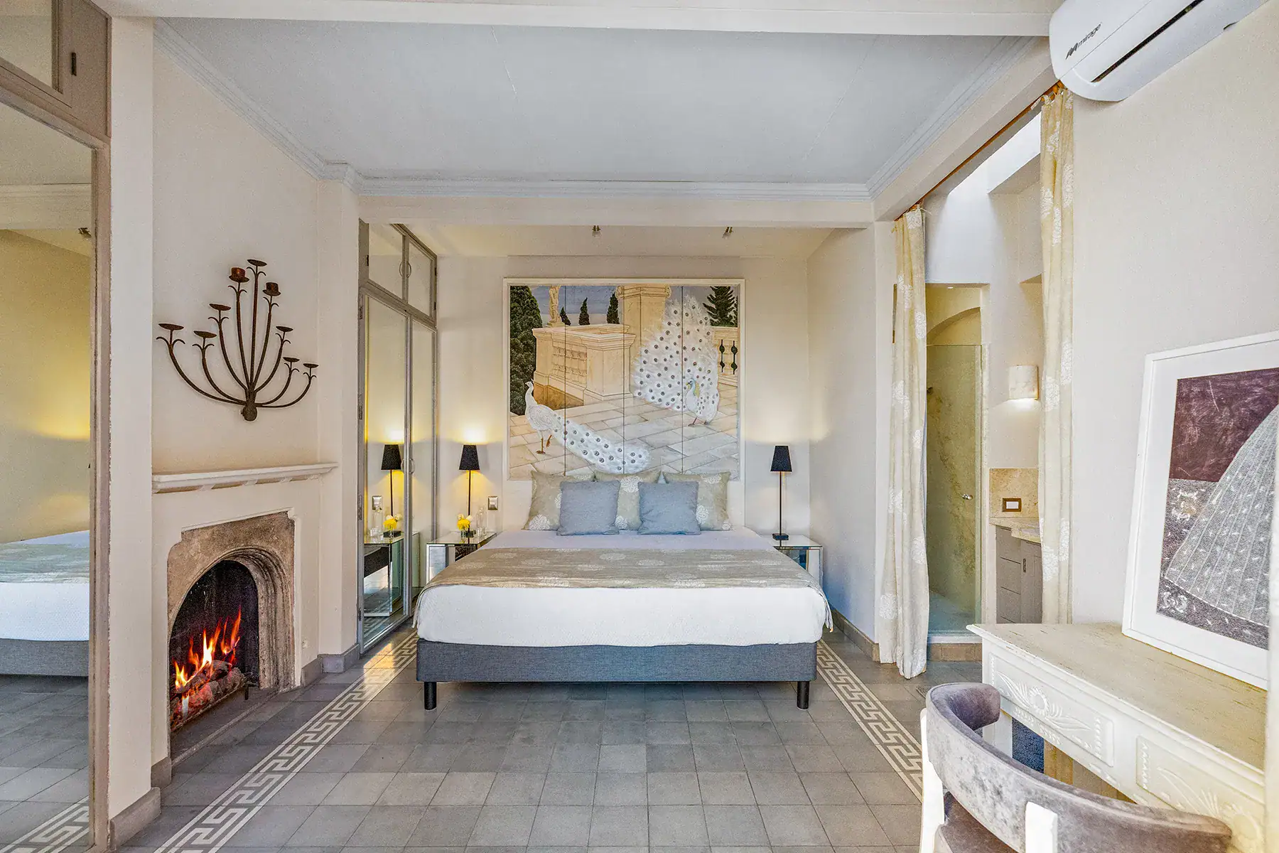 Casa White Magnolias, bedroom with a fireplace, framed art and a corner mirror, San Miguel de Allende