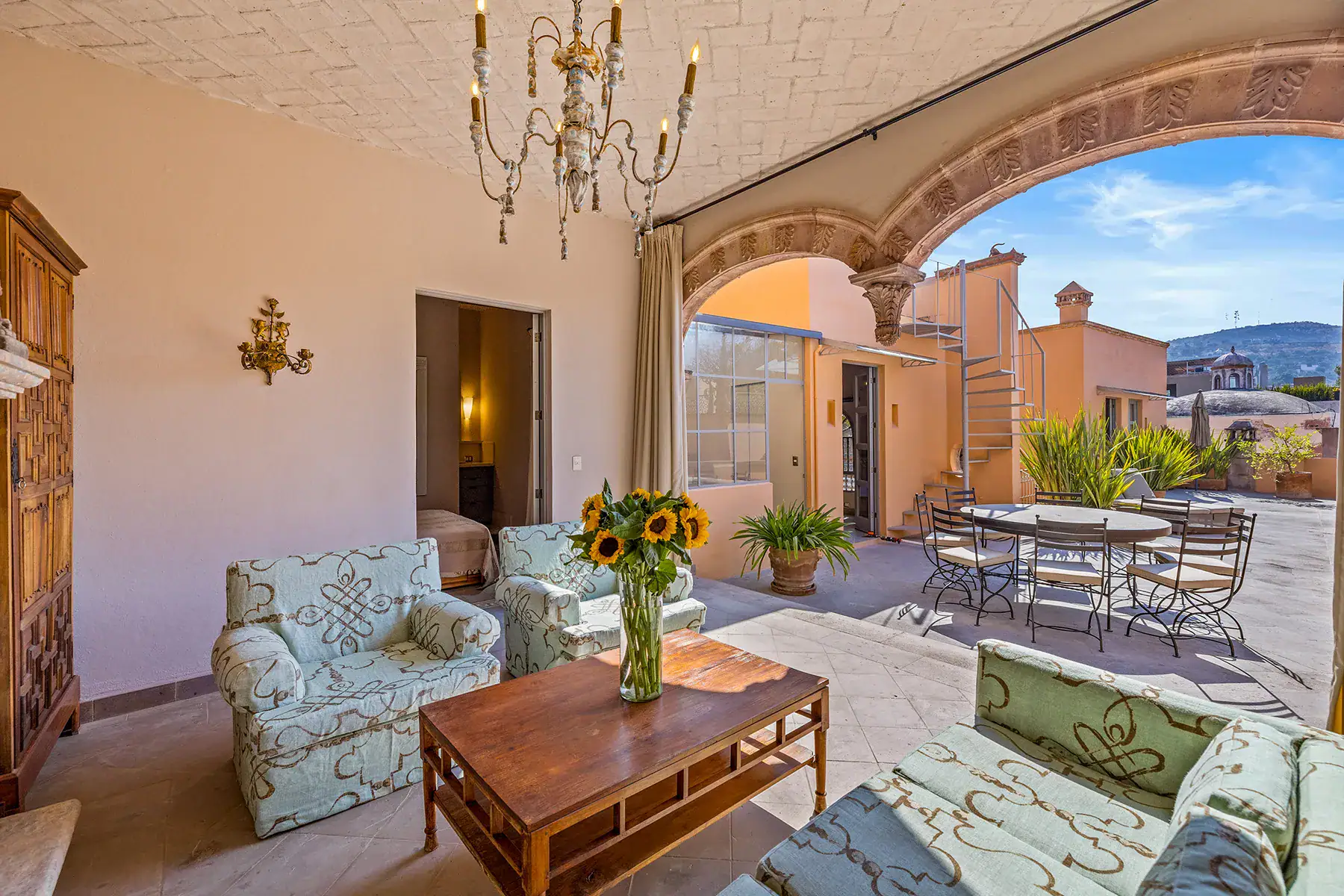 Casa White Magnolias, covered seating area with patterned armchairs and a wood coffee table opening to the terrace, San Miguel de Allende