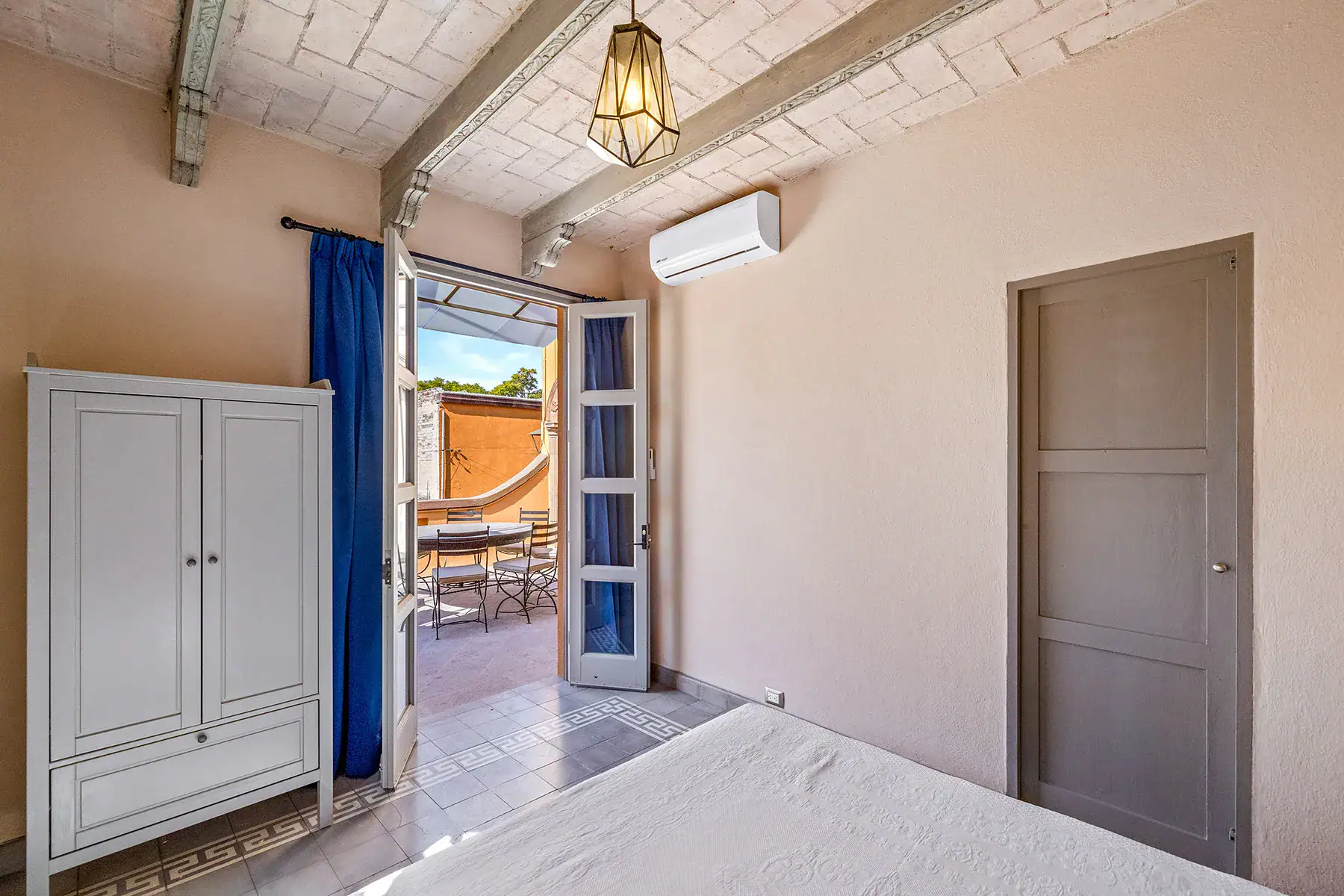 Casa White Magnolias, bedroom with French doors to the terrace, a wardrobe and a wall-mounted air conditioner, San Miguel de Allende