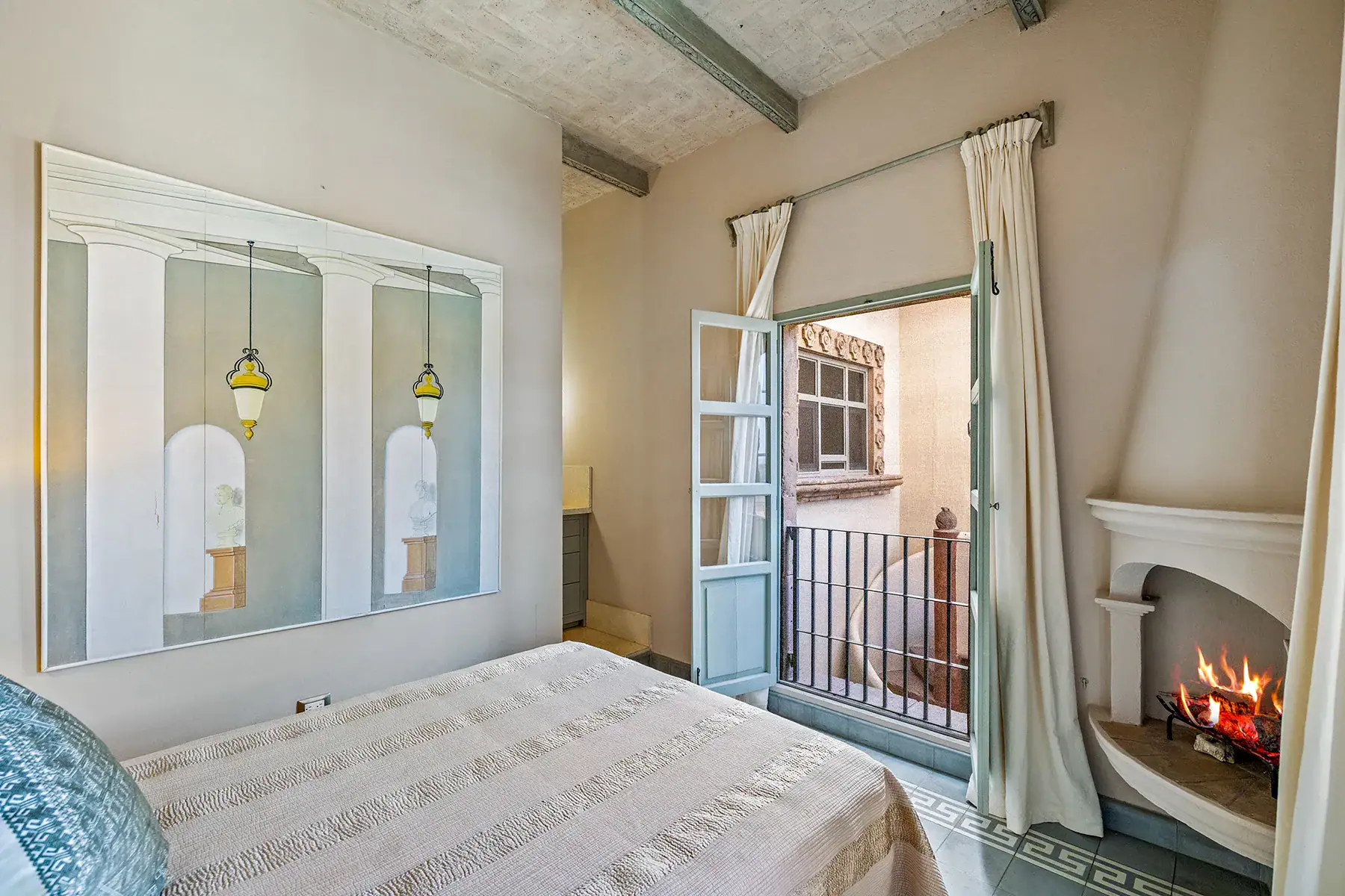 Casa White Magnolias, bedroom with a fireplace and French doors with a balcony railing, San Miguel de Allende