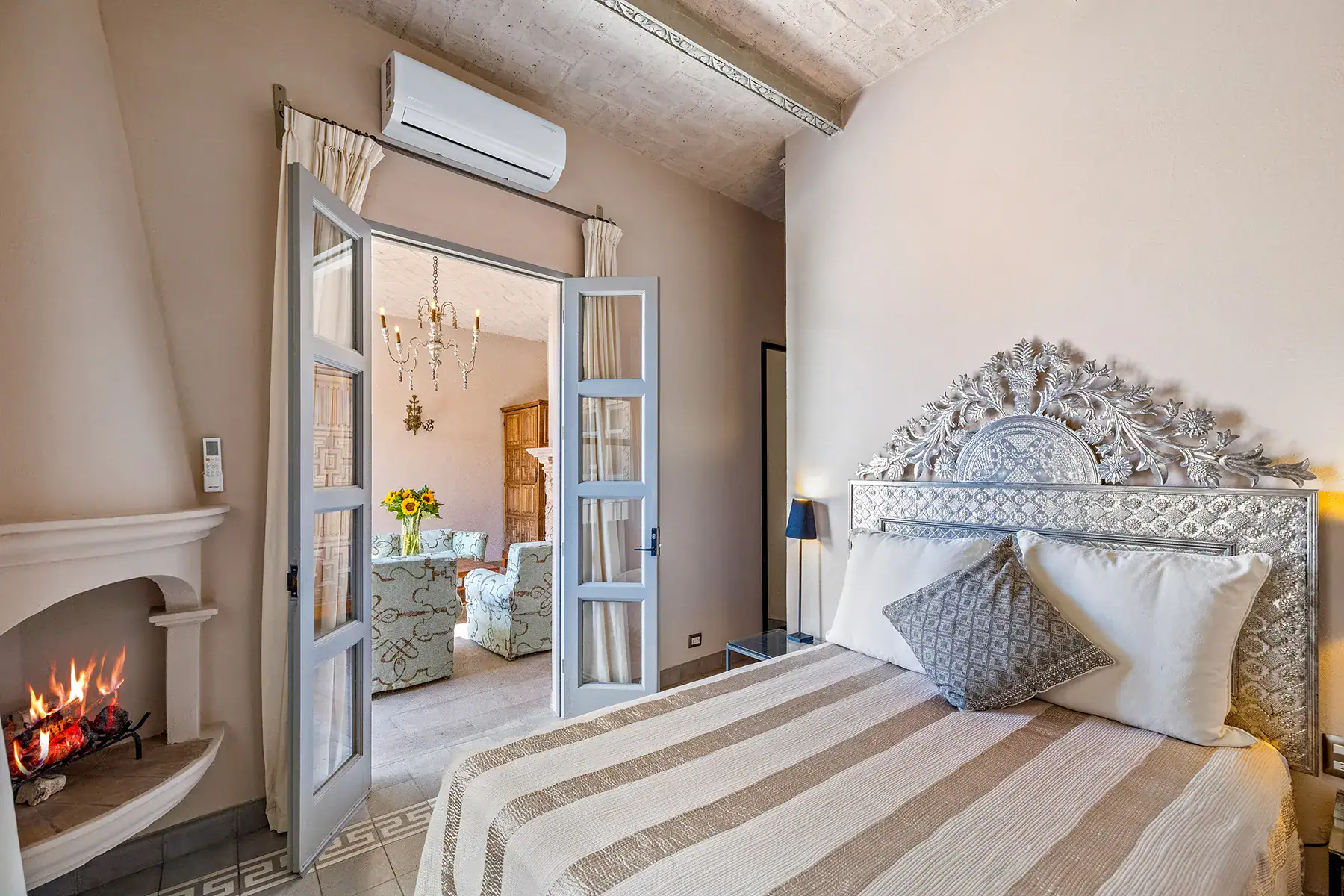 Casa White Magnolias, bedroom with a carved metal headboard, fireplace and French doors to the terrace, San Miguel de Allende