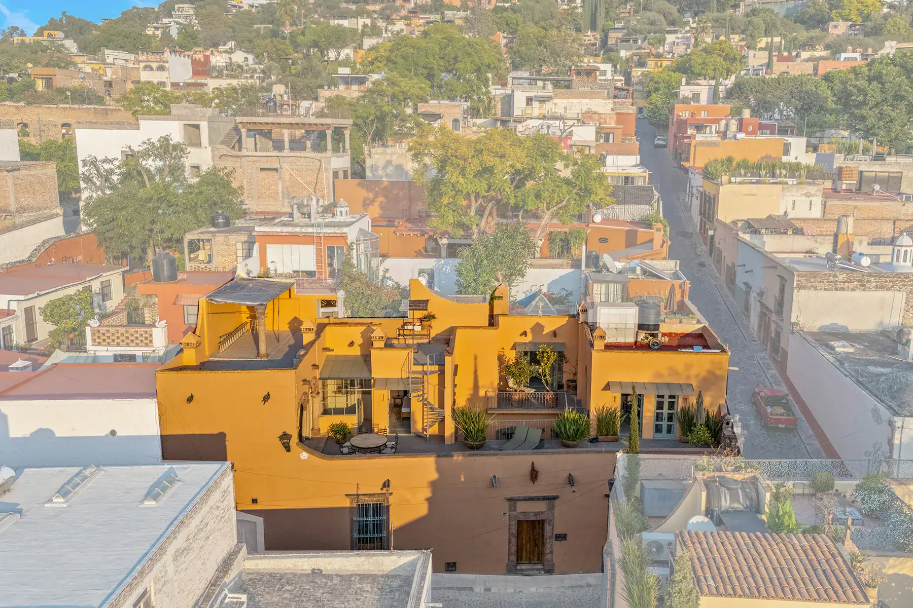 Casa White Magnolias, aerial view of the yellow house and its rooftop terrace among neighboring buildings, San Miguel de Allende