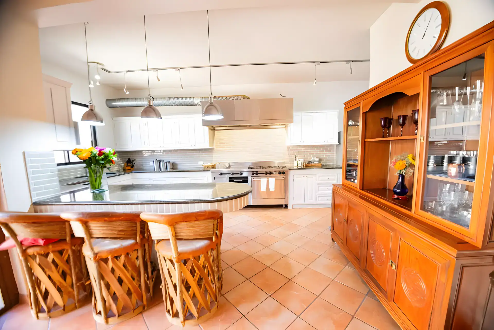 Casa Winston, kitchen island with three leather bar stools, a wood china hutch and a stainless hood, San Miguel de Allende