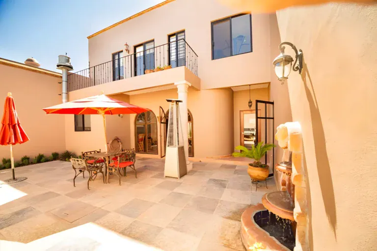 Casa Winston, courtyard patio with a stone floor, a red umbrella, a patio heater, a wrought-iron dining set and a fountain, San Miguel de Allende
