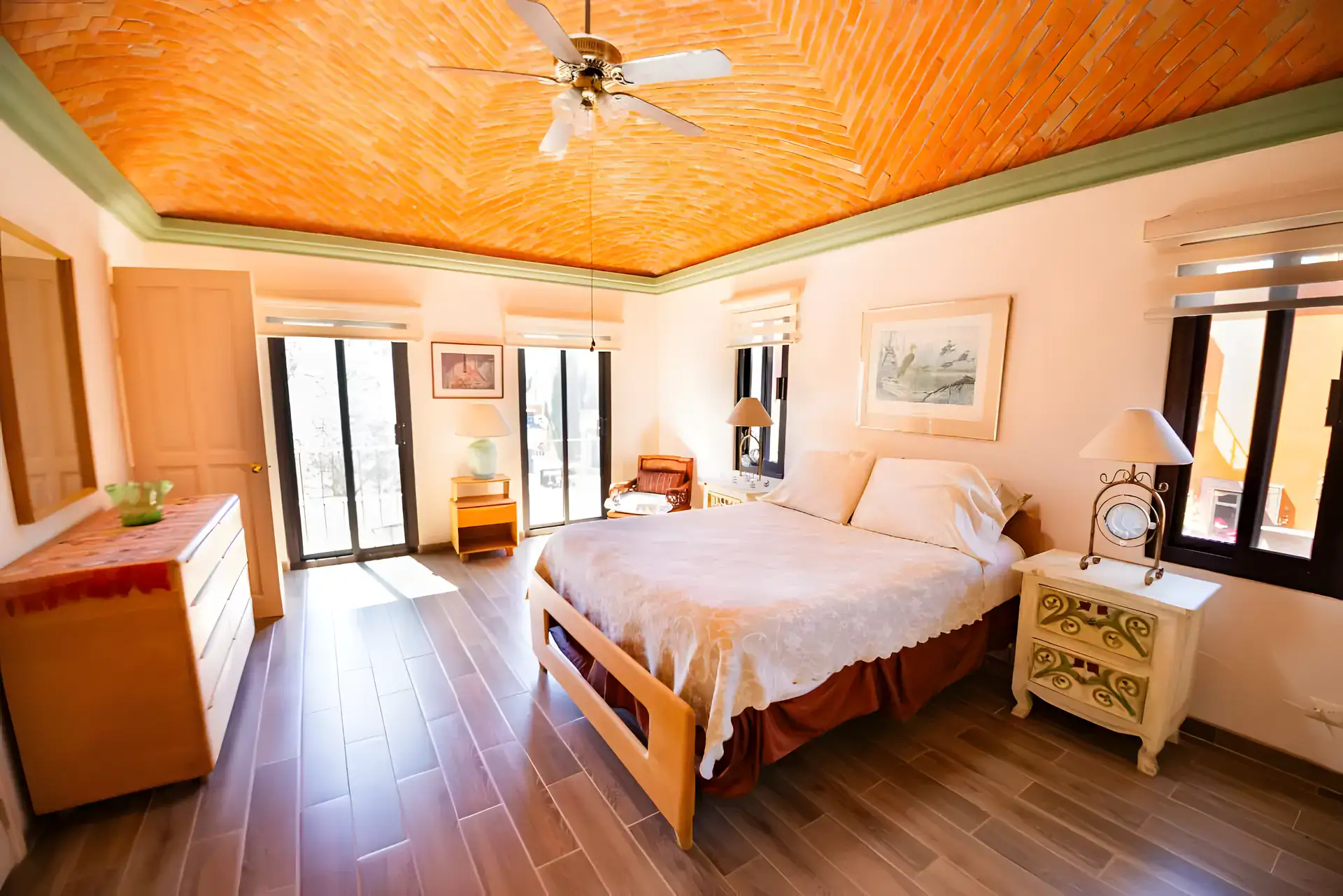 Casa Winston, bedroom with a brick vaulted ceiling, a wood bed with a lace spread and a sliding glass door to a balcony, San Miguel de Allende