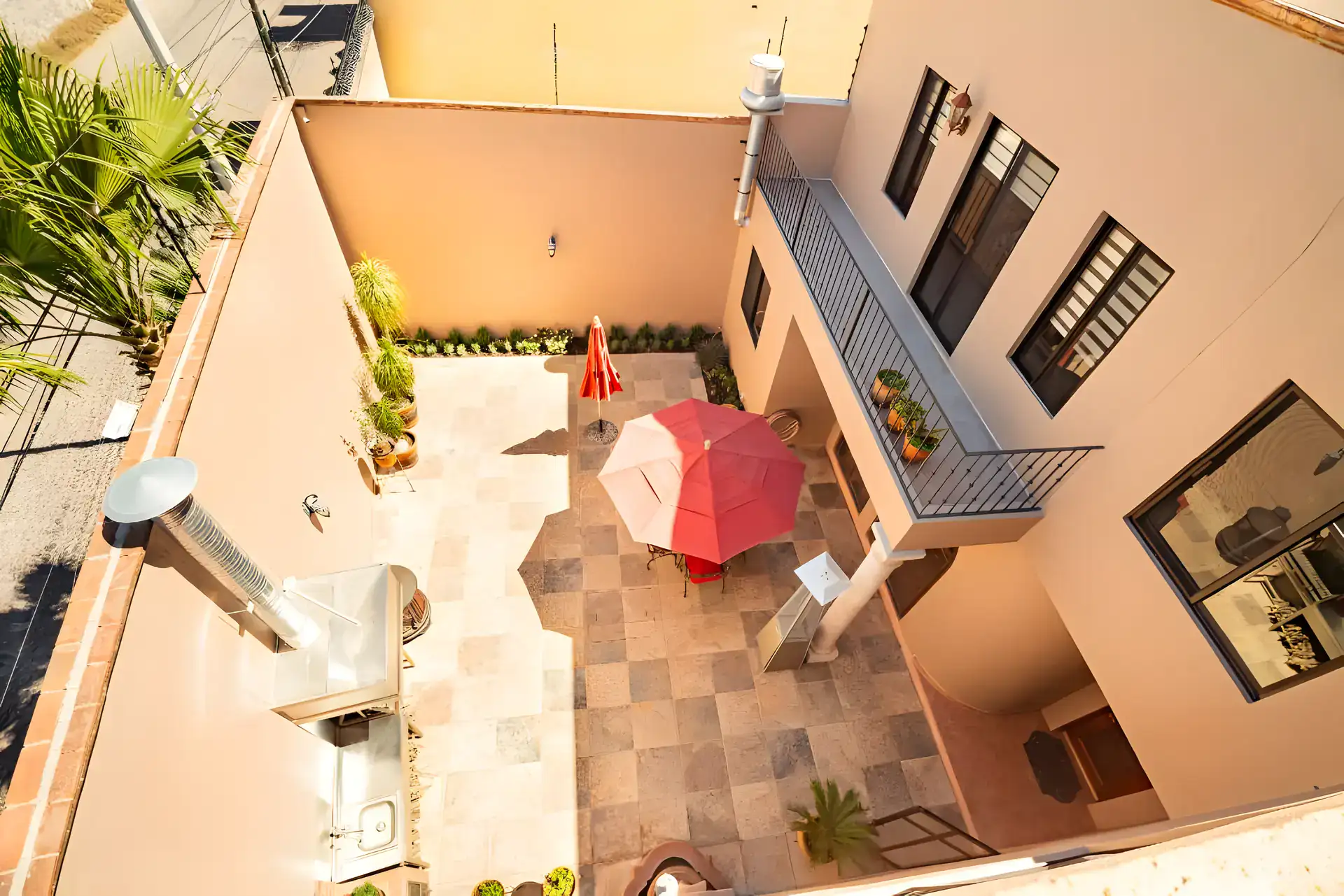 Casa Winston, aerial view down into the courtyard with a red umbrella, an outdoor kitchen and a balcony, San Miguel de Allende
