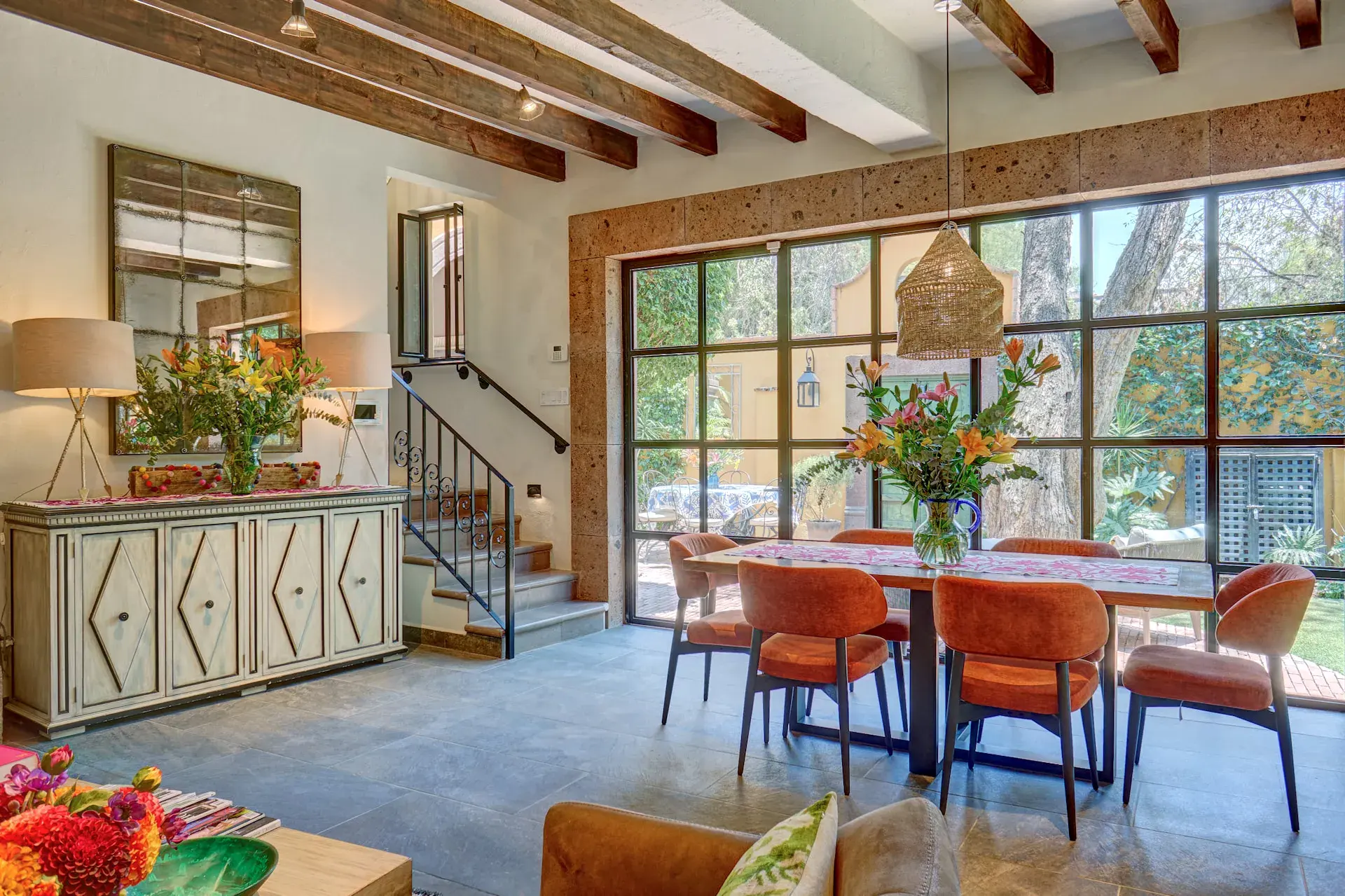 Casa Zaca, dining table with orange chairs and floor-to-ceiling glass doors, San Miguel de Allende