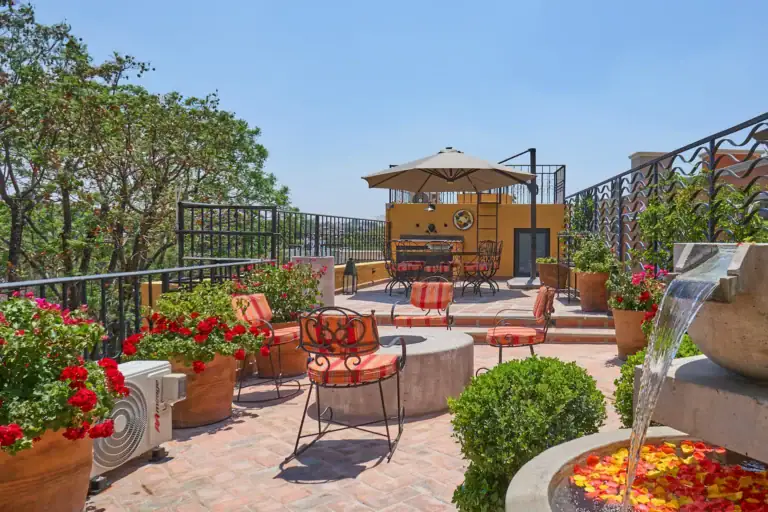 Casa Zaca, rooftop lounge with orange chairs, a fire pit and a view over the trees, San Miguel de Allende