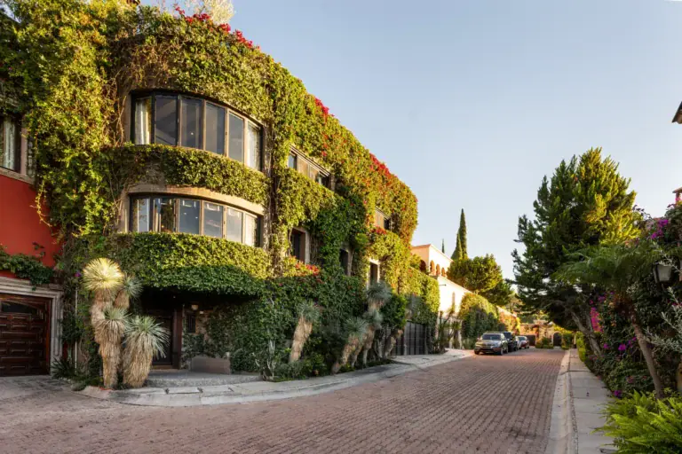 Casa Zen, ivy-covered facade with rounded bay windows on a brick street, San Miguel de Allende